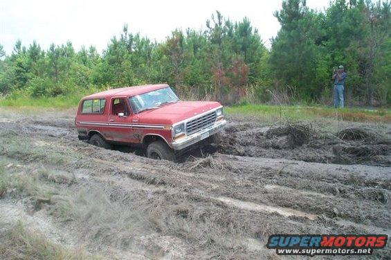 Red 1978 Ford Bronco stuck in mud, front 3/4 view