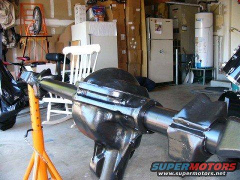 Black rear axle assembly on an orange jack stand in a garage