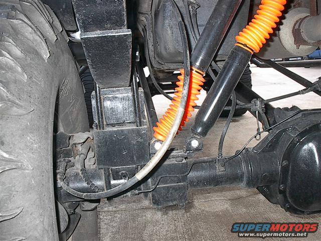 Rear axle and suspension with orange shock boots and large tire