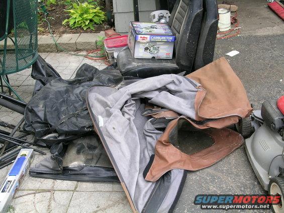 Pile of car parts including seats, a soft top, and a Holley carburetor box