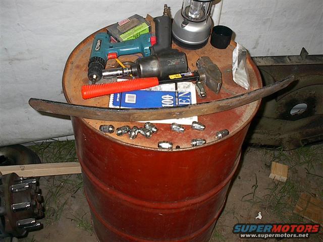 Leaf spring and tools on a red barrel. Includes drill, impact wrench, hammer, and lug nuts