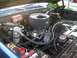 1979 Chevrolet C/K Pickup - The engine compartment of a blue pickup truck, showing the V8 engine and various components.
