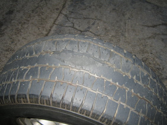 Tire with worn tread and visible cracks on sidewall