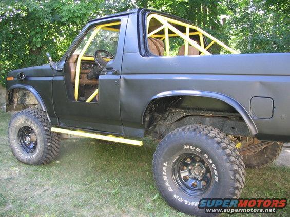 Black SUV with yellow roll cage and off-road tires, side view