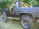 1986 Ford Bronco - This black SUV features a prominent yellow roll cage and aggressive off-road tires, viewed from the side.
