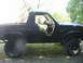 1986 Ford Bronco - This modified Ford Bronco features a prominent yellow roll cage and side steps, with its doors removed.