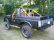 1986 Ford Bronco - This modified SUV features a prominent yellow roll cage and lifted suspension, with the front fender removed.