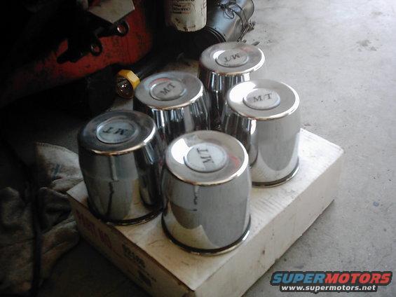 Five chrome hubcaps with MT logo on a cardboard box
