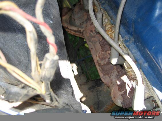 Rusty exhaust manifold and blue engine block with wiring