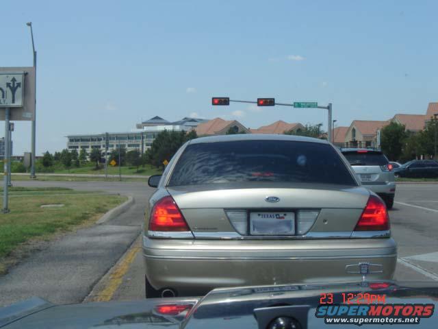 Gold Ford Crown Victoria rear view, Texas license plate, daytime traffic