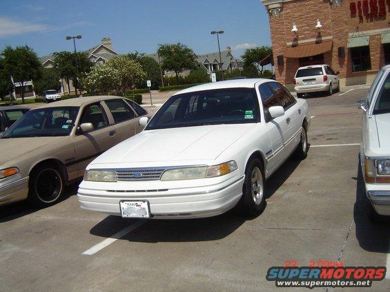 White sedan parked in a lot, front view. Texas license plate visible