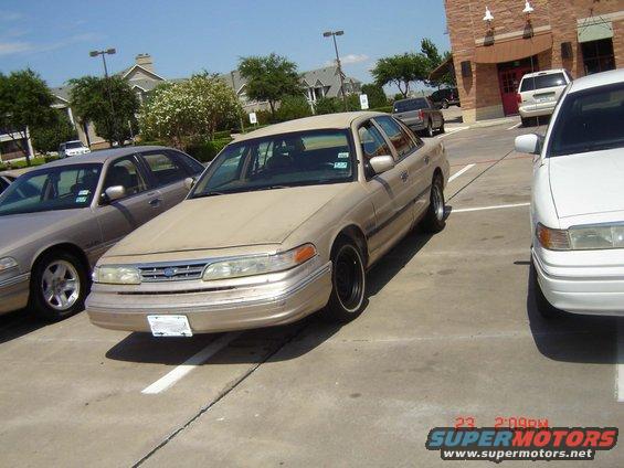 Tan Ford Crown Victoria parked next to a white Ford Crown Victoria