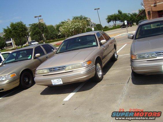 Tan 1990s Ford Crown Victoria sedan parked in a lot, front 3/4 view