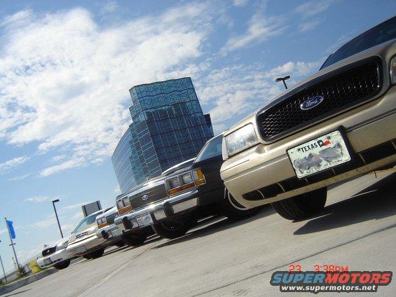 Gold 1998 Ford Crown Victoria front grille and Texas license plate, parked in a row with other cars