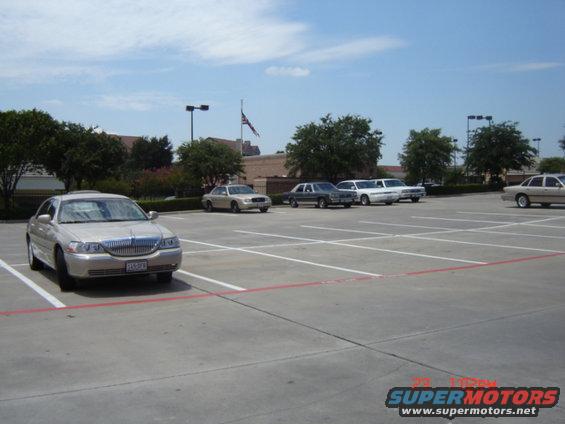 Silver Lincoln Town Car parked in a lot. Other cars are visible in the background