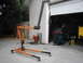 1978 Ford Bronco - An engine hoist stands ready in front of a garage containing a car, welding gear, and other automotive parts.