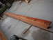1978 Ford Bronco - A long wooden beam is on a concrete surface, with sawdust scattered around it.
