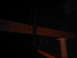 1978 Ford Bronco - A wooden beam is held up by a column, with an orange structure beneath it in the dark.