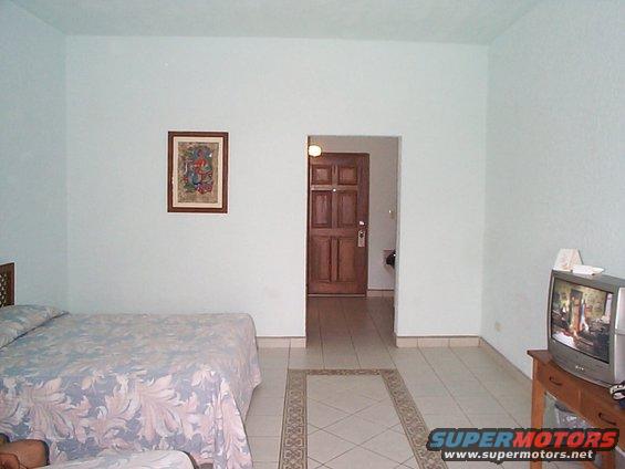 Hotel room with a bed, a doorway to another room, and a TV on a stand