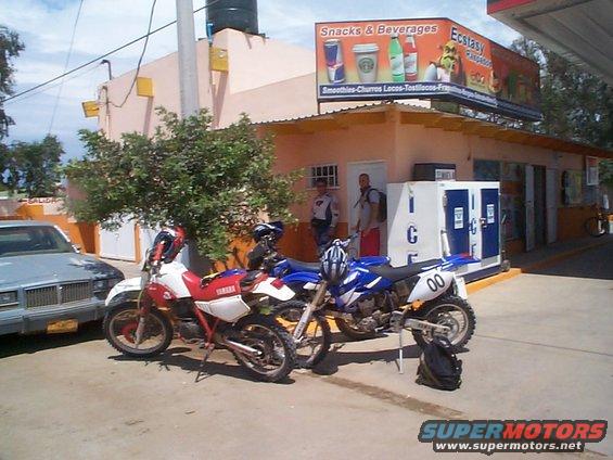 Red and blue dirt bikes parked outside a convenience store