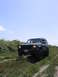 2000 Jeep Cherokee - A dark Jeep Cherokee drives off-road on a sunny day, its body style clearly indicating a 2000 model year.
