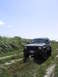 2000 Jeep Cherokee - Jeep Cherokee parked on a dirt road with green foliage under a blue sky.