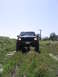 2000 Jeep Cherokee - Front view of a 2000 Jeep Cherokee driving on a dirt path with vegetation.