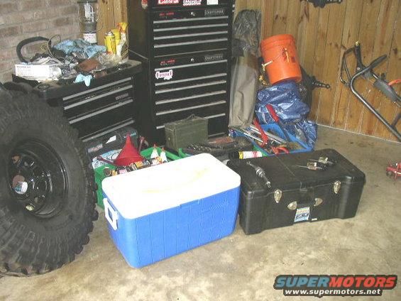 Big tire, tool chests, coolers, and buckets in a garage