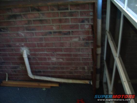 Brick wall with white pipes and a window frame. Supermotors.net logo visible