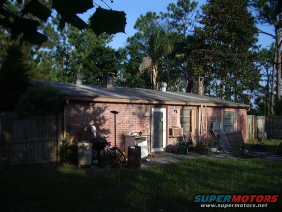 backyard with brick house, fence, grill, and bicycle
