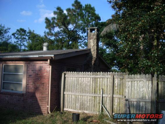 House with stone chimney and wooden fence