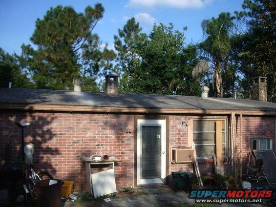 Backyard with brick building, trees, and some clutter