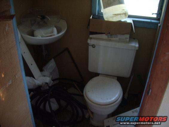Bathroom with sink, toilet, and boxes stacked near a window