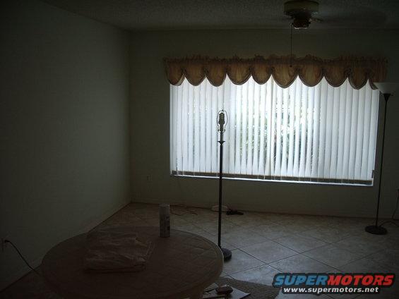 Interior room with blinds on window, floor lamp, and table