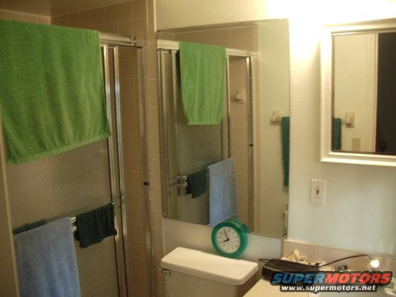 Bathroom with green towels and a clock on the toilet tank