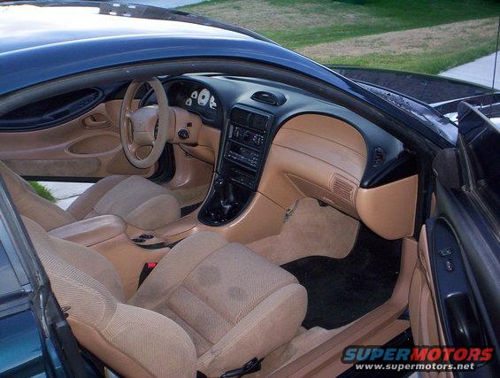 Tan interior of a 1994 Ford Mustang, showing dashboard, seats, and center console