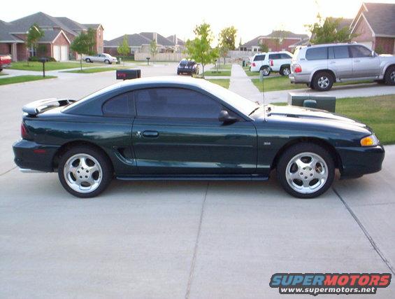 Dark green 1994 Ford Mustang coupe, side view, with a rear spoiler and five-spoke wheels