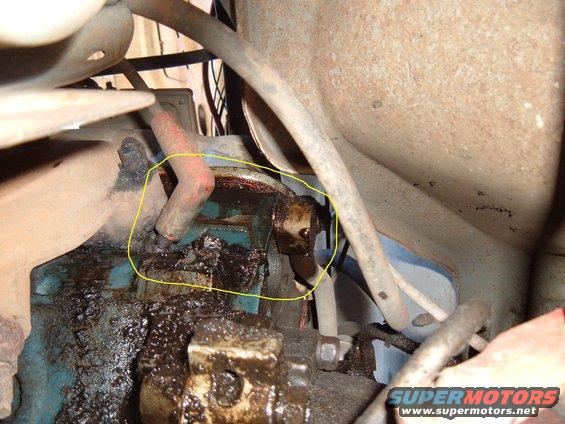 Close-up of engine component with oil leak, circled in yellow