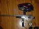 1995 Ford Mustang - A paintball marker is shown with its hopper and clear grip on a wooden table.