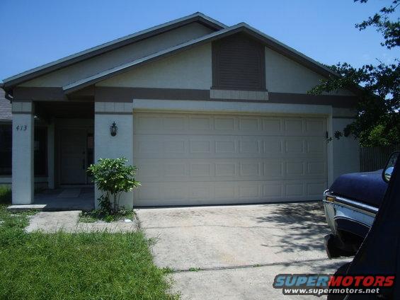 House with a beige garage door and a blue vehicle parked in the driveway