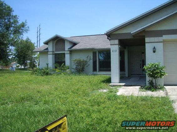 House with overgrown grass and a white garage door