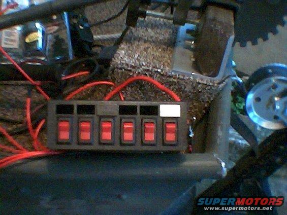 Aftermarket switch panel with six red toggle switches and visible red wiring