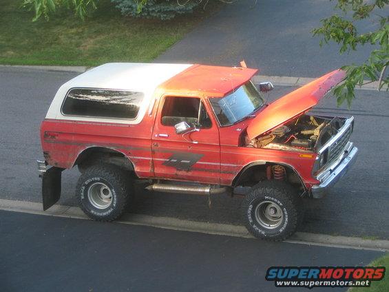 Red and white 1978 Ford Bronco with hood open, lifted suspension, and off-road tires