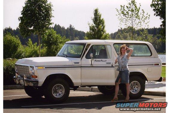 White Ford Bronco with a woman standing next to it. The vehicle has a two-tone paint scheme and chrome accents