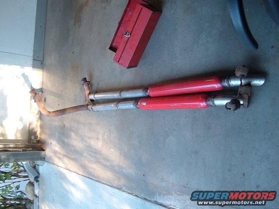 Dual exhaust pipes with red mufflers and a red toolbox