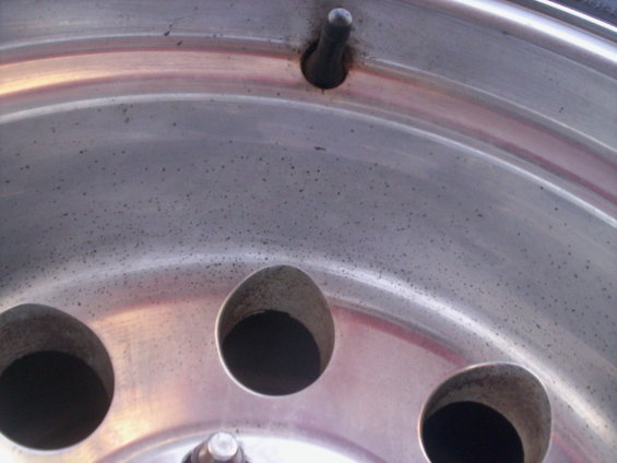 Close-up of an aluminum alloy wheel showing three lug nut holes and a valve stem