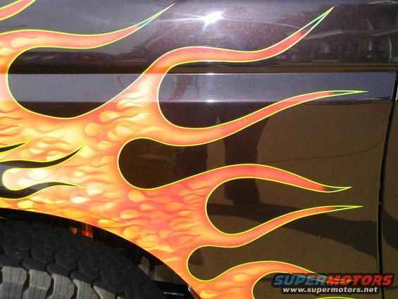 close-up of flame graphics on a dark vehicle side panel, showing tire tread