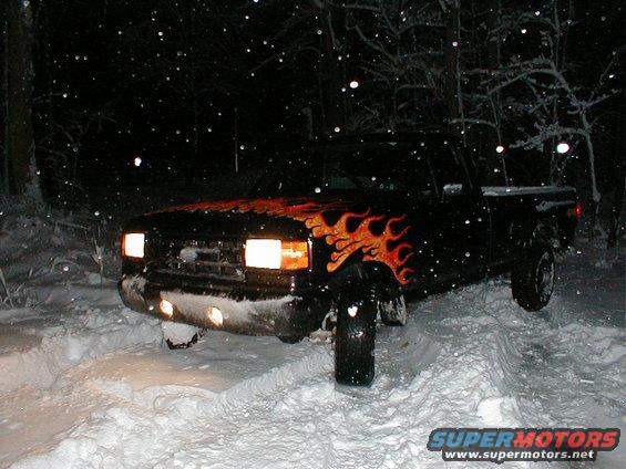 Black pickup truck with flame decals stuck in snow, front view