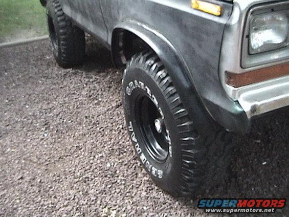 Front fender and tire of a dark-colored Ford Bronco. Tire has white lettering that says "GOODRICH RADIAL"