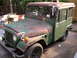 1973 Jeep CJ5 - This weathered panel van, possibly a modified Jeep, sits in a yard with visible rust and a custom rear cargo area.